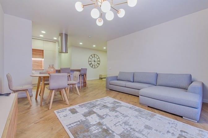 Modern living room with a grey sectional sofa, dining area, and minimalist decor