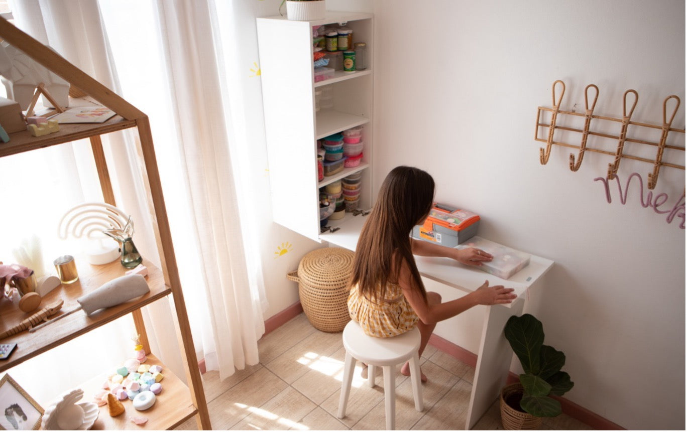 Girl using compact folding wall desk in bright, organized small room with smart storage shelves