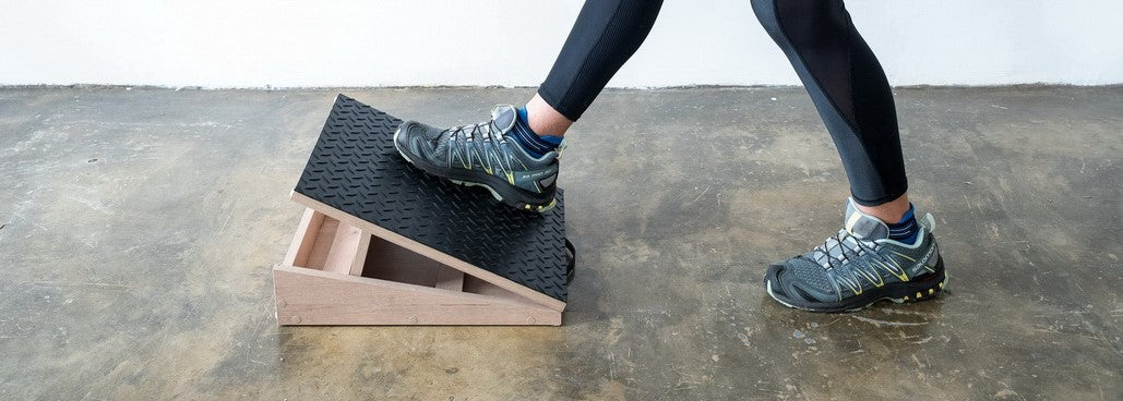 Adjustable wooden footrest and exercise slant board in use on concrete floor